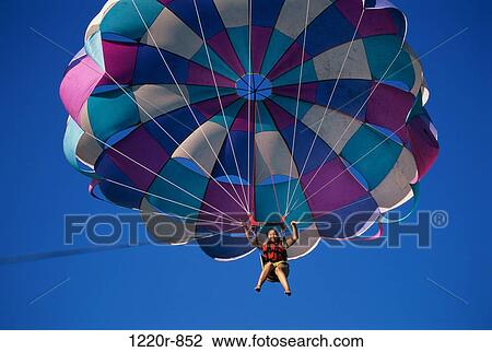 Low angle view of a person parasailing View Large Photo Image Stock Image - Low angle view of a person parasailing. Fotosearch