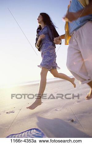 Low angle view of a young couple running together at the beach View Large Photo Image Stock Image - Low angle view of a young couple running together at the beach. Fotosearch