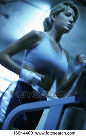 Low angle view of a young woman running on a treadmill View Large Photo Image Stock Image - Low angle view of a young woman running on a treadmill. Fotosearch