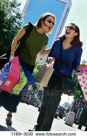 Low angle view of a young woman carrying shopping bags View Large Photo Image Stock Image - Low angle view of a young woman carrying shopping bags. Fotosearch