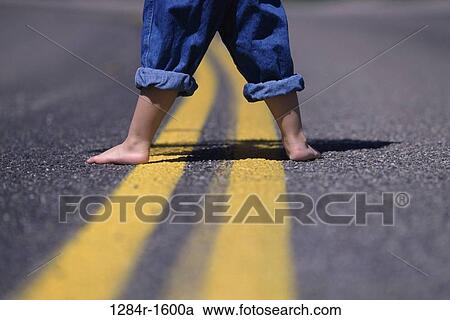 Low section view of a person's feet standing on a road View Large Photo Image Stock Image - Low section view of a person's feet standing on a road. Fotosearch