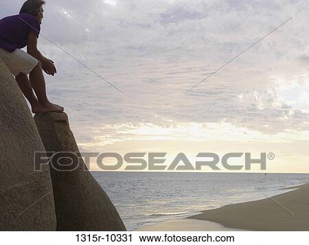 Mexico, Baja California, Man enjoying sunset view from rocks above beach View Large Photo Image Stock Image - Mexico, Baja California, Man enjoying sunset view from rocks above beach. Fotosearch