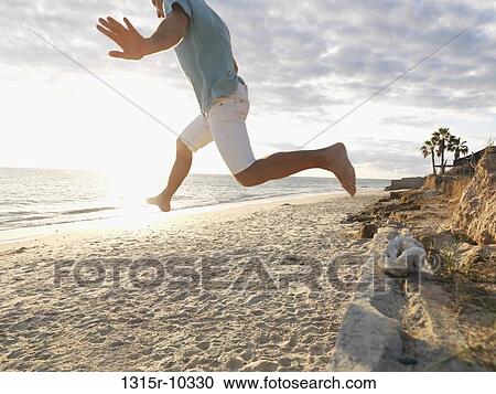 Mexico, Baja California, Man jumping from stone wall onto beach View Large Photo Image Stock Image - Mexico, Baja California, Man jumping from stone wall onto beach. Fotosearch