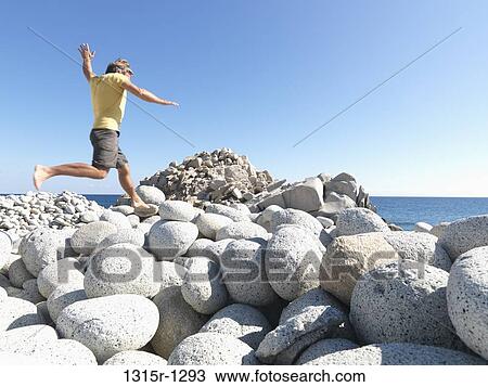 Mexico, Baja California, man jumping between boulders above edge of sea View Large Photo Image Stock Image - Mexico, Baja California, man jumping between boulders above edge of sea. Fotosearch