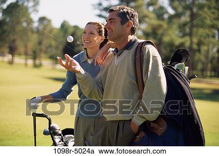 Stock Image - Mid adult couple on a golf course. Fotosearch