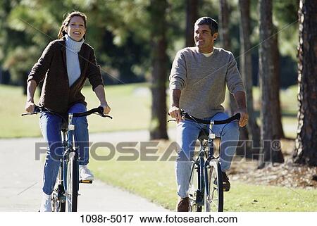 Mid adult couple riding bicycles together View Large Photo Image Stock Photo - Mid adult couple riding bicycles together. Fotosearch