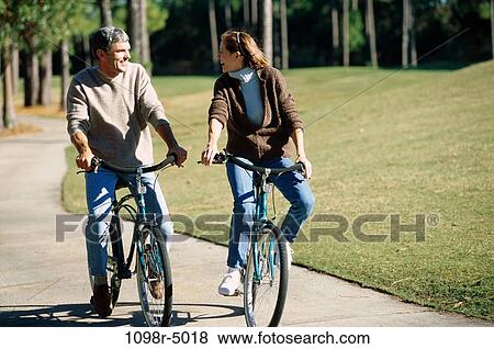 Mid adult couple riding bicycles together View Large Photo Image Stock Photo - Mid adult couple riding bicycles together. Fotosearch