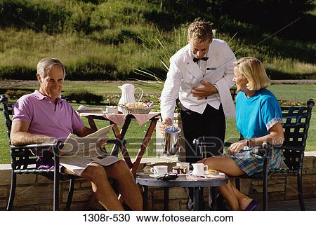Mid adult couple served by a waiter outdoors View Large Photo Image Stock Image - Mid adult couple served by a waiter outdoors. Fotosearch