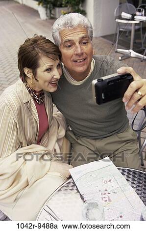 Mid adult couple taking a photograph of themselves View Large Photo Image Stock Image - Mid adult couple taking a photograph of themselves. Fotosearch