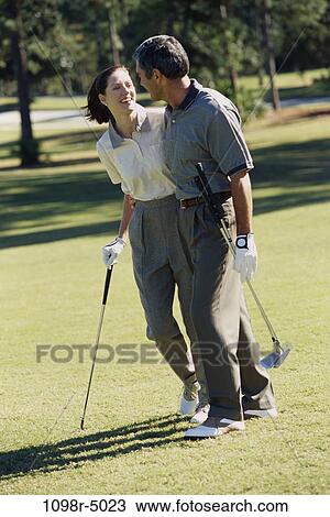 Mid adult couple walking on a golf course View Large Photo Image Stock Image - Mid adult couple walking on a golf course. Fotosearch