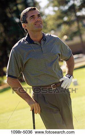 Stock Photograph - Mid adult man holding a golf club. Fotosearch