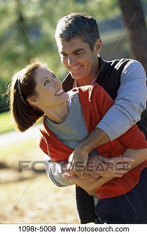 Stock Photo - Mid adult man holding a mid adult woman. Fotosearch