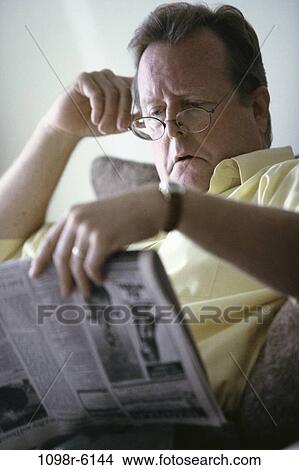 Picture - Mid adult man reading a newspaper. Fotosearch