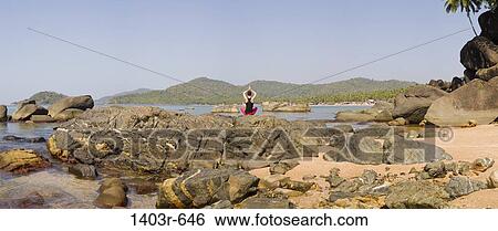 Stock Photograph - Mid adult woman meditating on the beach, Palolem Beach, Goa, India. Fotosearch