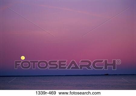 Stock Photo - Moon over an ocean at dusk. Fotosearch