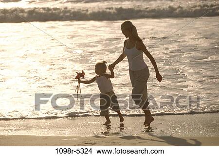 Mother and her daughter walking on the beach View Large Photo Image Picture - Mother and her daughter walking on the beach. Fotosearch