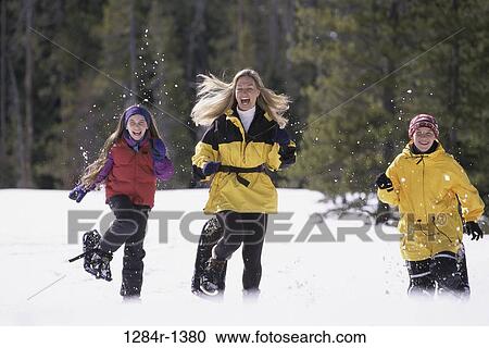 Stock Image - Mother and her two children running in the snow. Fotosearch