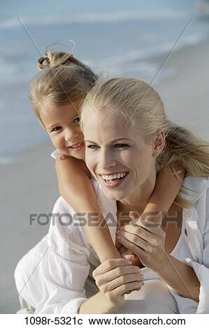 Stock Image - Mother carrying her daughter on her back. Fotosearch