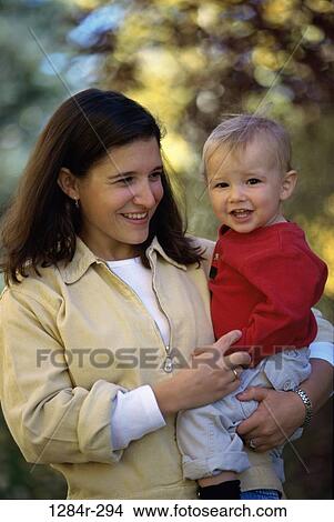 Mother holding her baby boy in a park smiling View Large Photo Image Picture - Mother holding her baby boy in a park smiling. Fotosearch