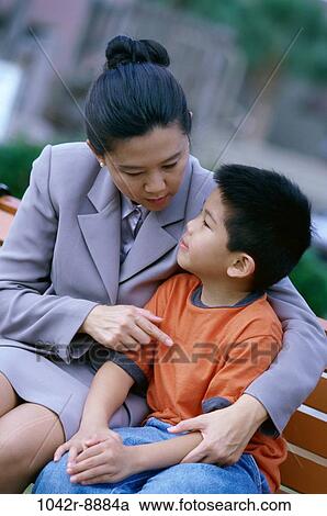 Mother sitting on a park bench with her son View Large Photo Image Stock Image - Mother sitting on a park bench with her son. Fotosearch