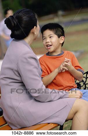 Mother sitting on a park bench with her son View Large Photo Image Stock Photograph - Mother sitting on a park bench with her son. Fotosearch