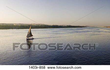 Panoramic view of a felucca sailing down the Nile River at sunset at Aswan, Egypt View Large Photo Image Stock Photo - Panoramic view of a felucca sailing down the Nile River at sunset at Aswan, Egypt. Fotosearch