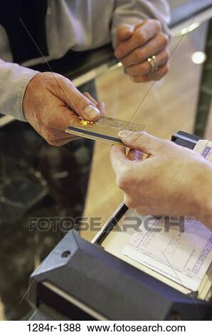Stock Photo - Person handing a credit card to a store attendant. Fotosearch