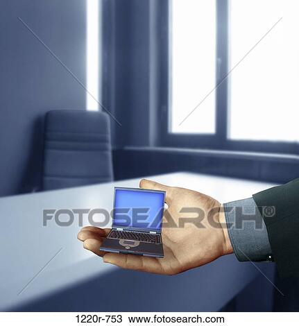 Stock Image - Person's hand holding a miniature laptop. Fotosearch