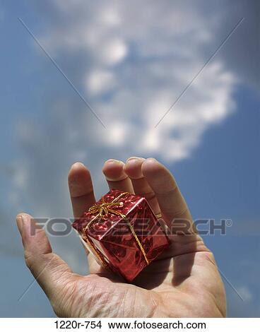 Picture - Person's hand holding a wrapped gift. Fotosearch