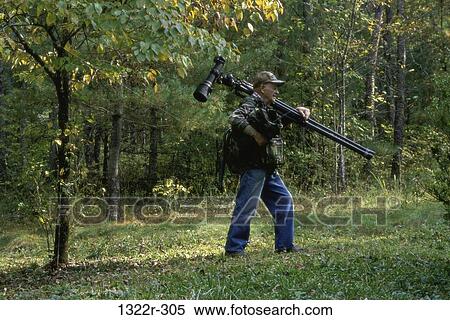 Photographer carrying a camera on a tripod View Large Photo Image Stock Photography - Photographer carrying a camera on a tripod. Fotosearch