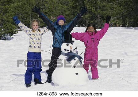 Portrait of a boy and two girls standing near a snowman with their arms raised View Large Photo Image Stock Photo - Portrait of a boy and two girls standing near a snowman with their arms raised. Fotosearch