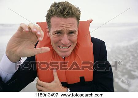 Portrait of a businessman standing at the beach wearing a life jacket View Large Photo Image Stock Photo - Portrait of a businessman standing at the beach wearing a life jacket. Fotosearch