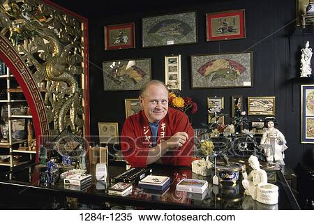 Stock Photography - Portrait of a businessman standing behind a counter in a store. Fotosearch