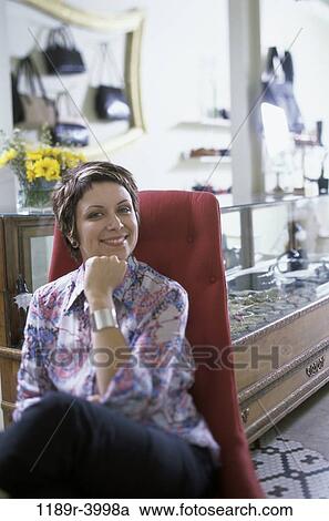 Stock Image - Portrait of a businesswoman sitting in a chair smiling. Fotosearch