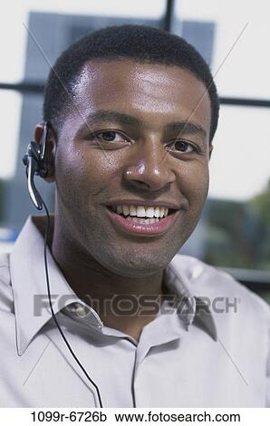 Stock Image - Portrait of a customer service representative wearing a headset smiling. Fotosearch