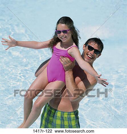 Stock Image - Portrait of a father holding his daughter at the beach. Fotosearch