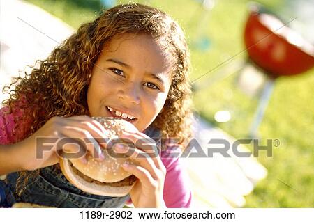 Portrait of a girl eating a hamburger View Large Photo Image Stock Image - Portrait of a girl eating a hamburger. Fotosearch