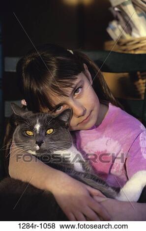 Stock Photo - Portrait of a girl holding a cat. Fotosearch