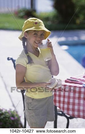 Stock Photo - Portrait of a girl holding a glass and a hamburger. Fotosearch