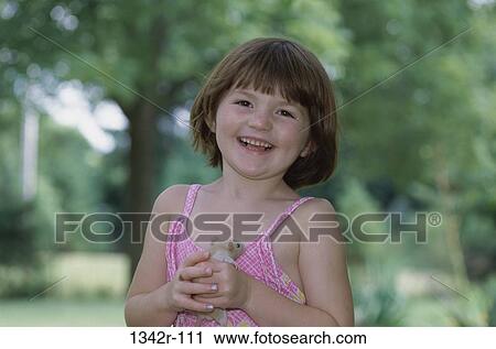 Stock Image - Portrait of a girl holding a hamster. Fotosearch