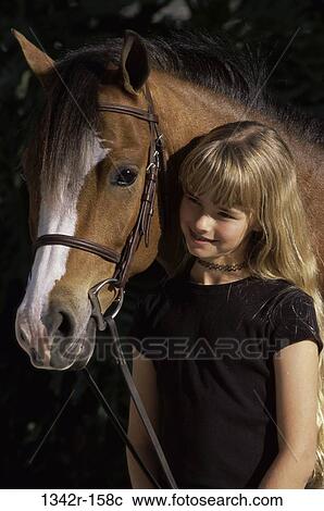 Stock Image - Portrait of a girl holding a Welsh pony. Fotosearch