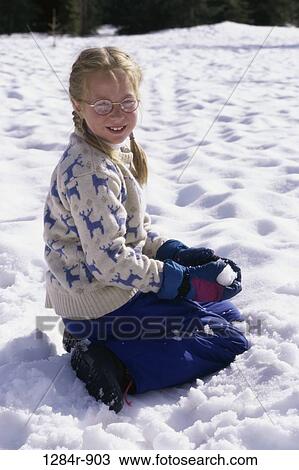 Stock Image - Portrait of a girl sitting in the snow. Fotosearch