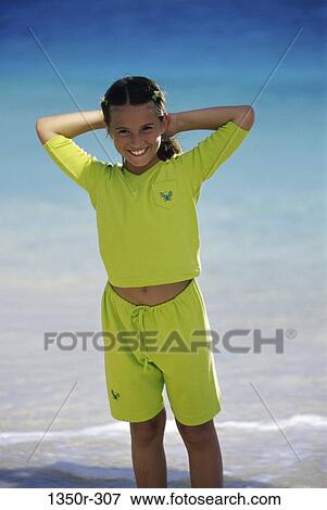 Portrait of a girl standing on the beach with her hands behind her head View Large Photo Image Stock Photo - Portrait of a girl standing on the beach with her hands behind her head. Fotosearch