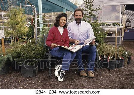 Portrait of a mid adult couple sitting together outdoors and holding documents View Large Photo Image Picture - Portrait of a mid adult couple sitting together outdoors and holding documents. Fotosearch