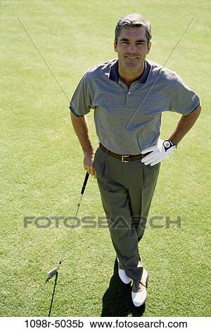 Stock Image - Portrait of a mid adult man holding a golf club. Fotosearch