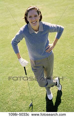 Stock Image - Portrait of a mid adult woman standing on a golf course. Fotosearch