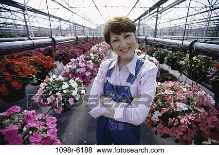 Stock Photo - Portrait of a mid adult woman standing in a greenhouse. Fotosearch