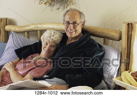 Portrait of a senior couple lying together in bed View Large Photo Image Stock Image - Portrait of a senior couple lying together in bed. Fotosearch