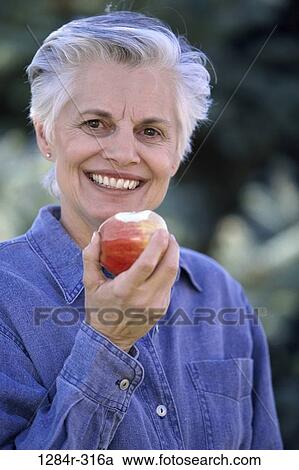 Portrait of a senior woman eating an apple View Large Photo Image Stock Image - Portrait of a senior woman eating an apple. Fotosearch