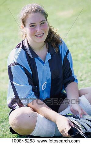 Stock Image - Portrait of a teenage girl sitting on a lawn smiling. Fotosearch